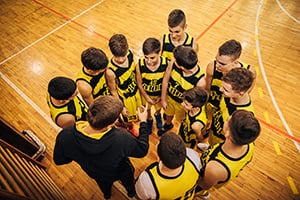 Boys basketball team huddle before the game, ensured fair play through roster management tracking tool